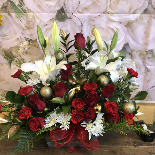 Red roses and white lilies arranged with gold ornaments in a red ribboned basket