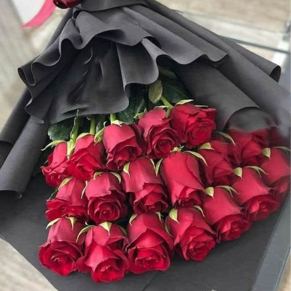 Bouquet of red roses wrapped in black paper with a pink ribbon