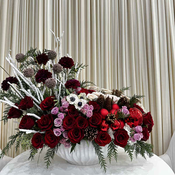 Large red and pink floral arrangement in a white vase