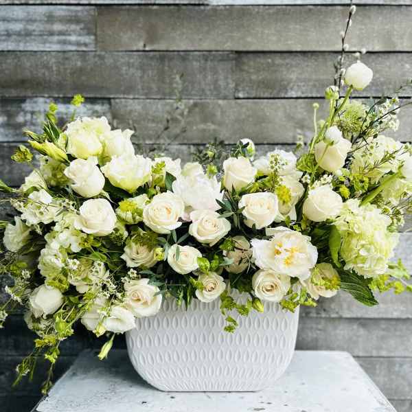 White roses and mixed white flowers in a textured white vase