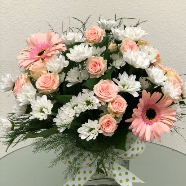 Pink gerbera daisies and pale roses with white daisies in a glass vase