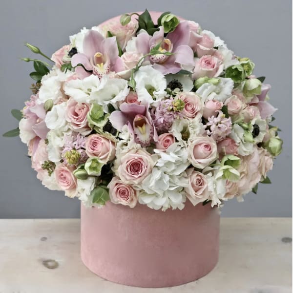Pink and white flower arrangement in a round pink box
