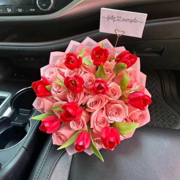 Bouquet of pink roses and red tulips with a small card