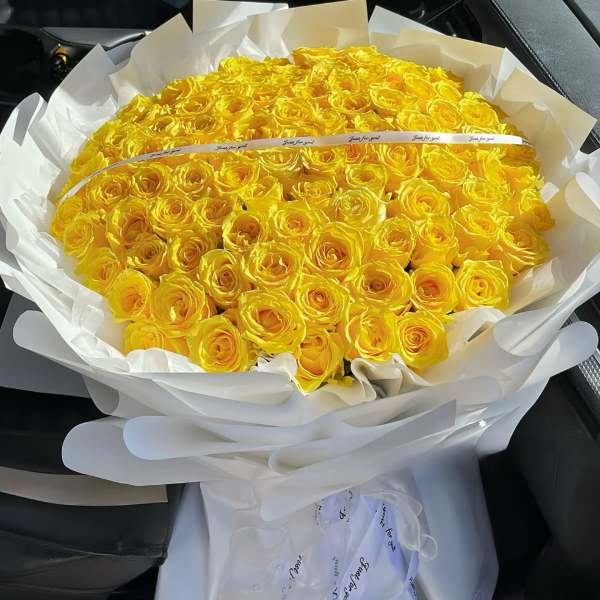 Large bouquet of yellow roses wrapped in white paper