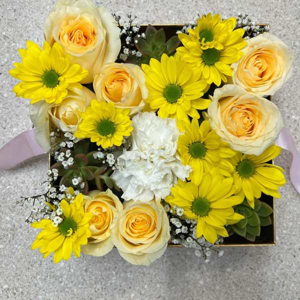 Yellow daisies and cream roses arranged in a square box