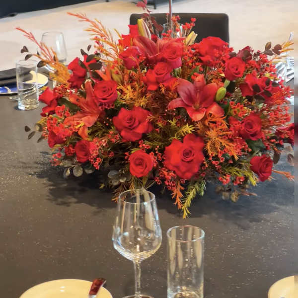 Large red rose centerpiece with orange accents on a banquet table