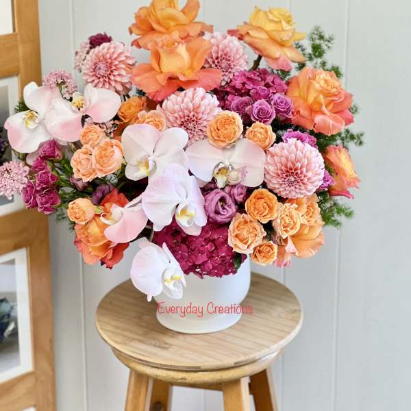 Bouquet of orange, pink, and white flowers in a white vase