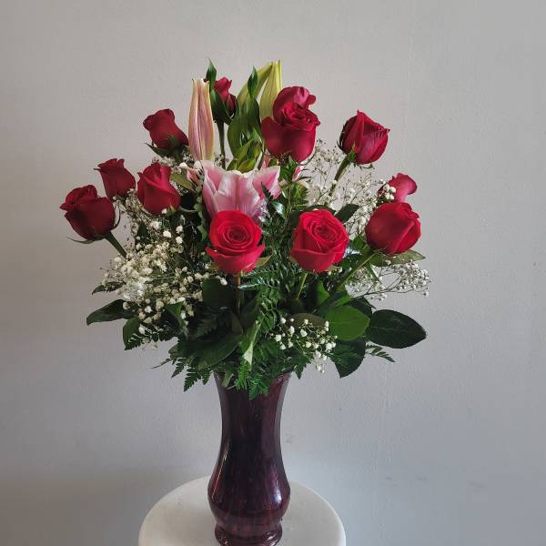 Red roses and pink lilies in a purple glass vase