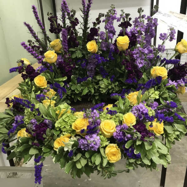 Large wreath of yellow roses and purple flowers on a stand