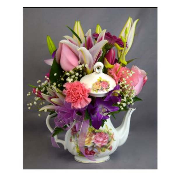 Bouquet of pink and purple flowers in a floral teapot vase