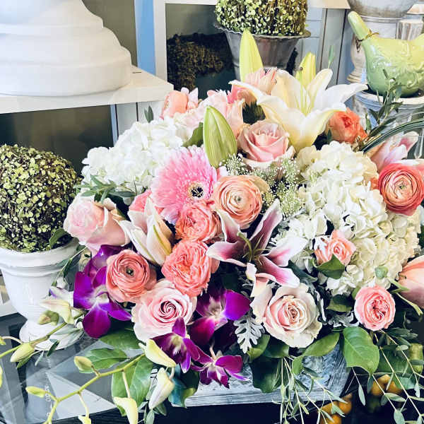 Mixed bouquet with pink roses, white lilies, and purple orchids in a container
