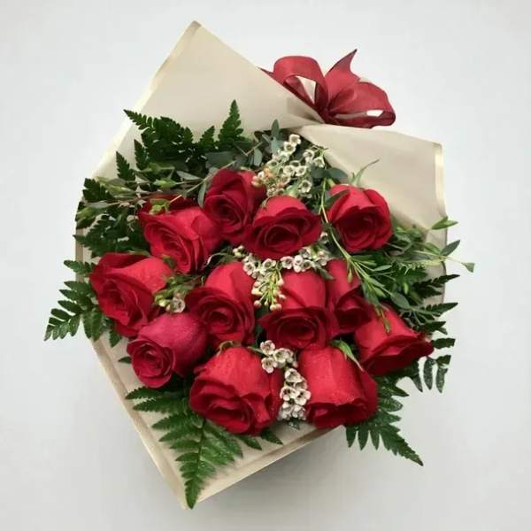 Bouquet of red roses wrapped in cream paper with a red ribbon