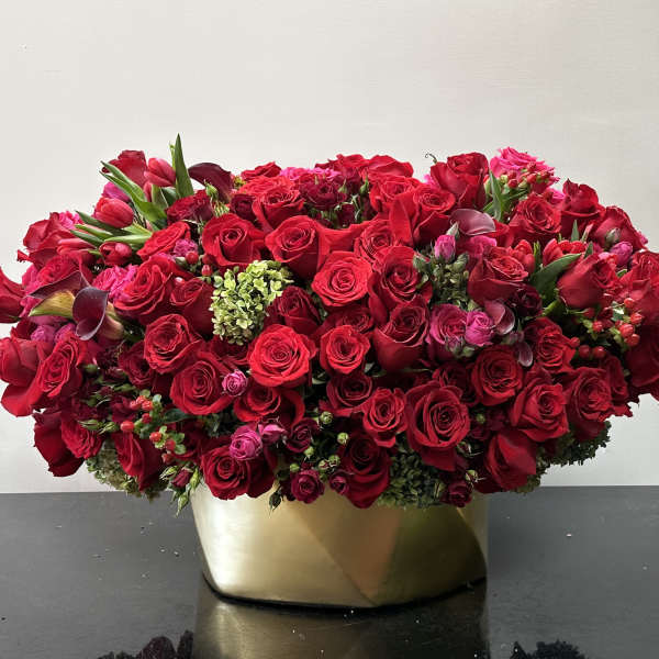 Dense red rose arrangement in a gold vase