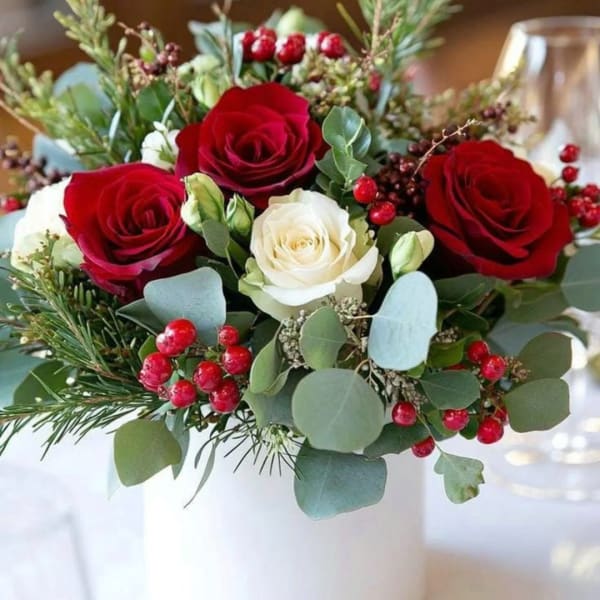 Bouquet of red and white roses with berries in a white vase