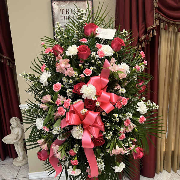 Large standing floral spray with pink and white flowers and a pink ribbon