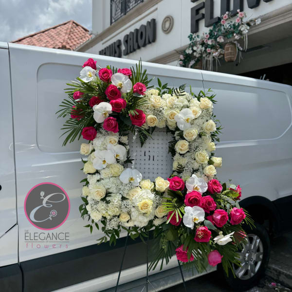 Large floral wreath on a stand with pink and white roses and orchids