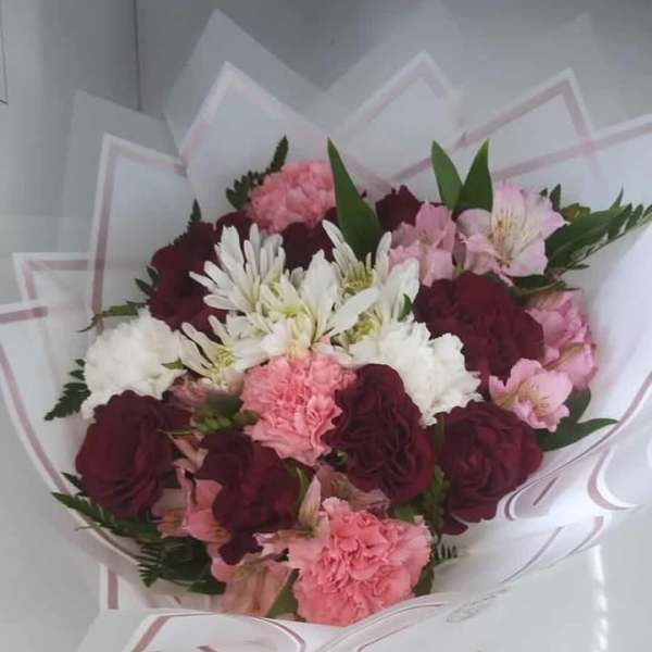 Bouquet of pink, burgundy, and white flowers wrapped in white paper