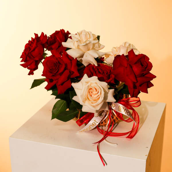 Red and white roses in a small basket with ribbon