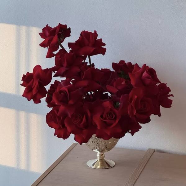 Red roses arranged in a decorative silver vase