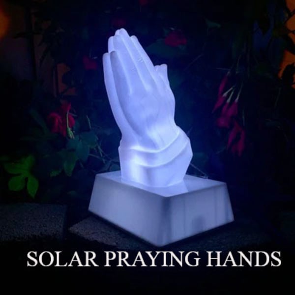 Illuminated praying hands statue on a pedestal