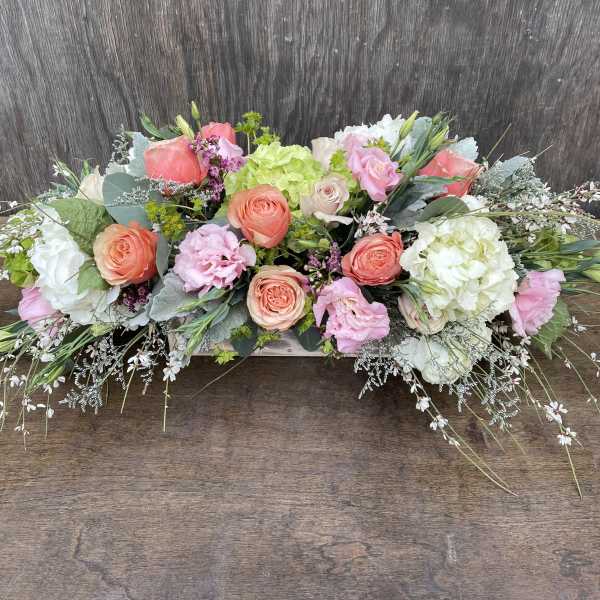 Low floral arrangement with pink, peach, and white blooms