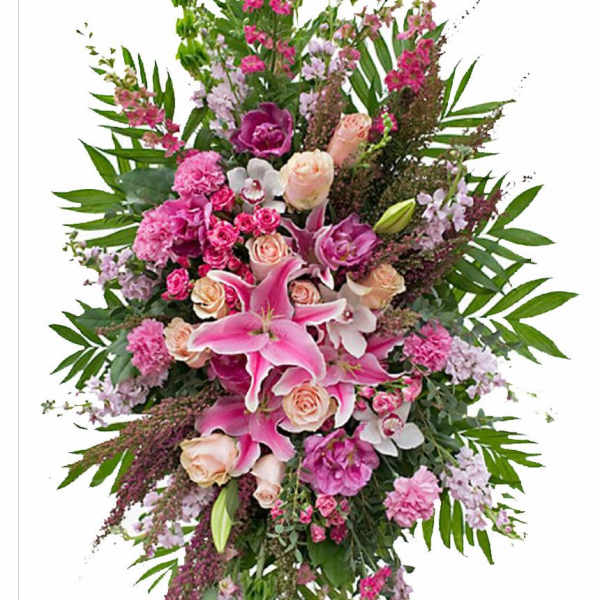 Tall standing spray of pink lilies, roses, carnations, and orchids on an easel.