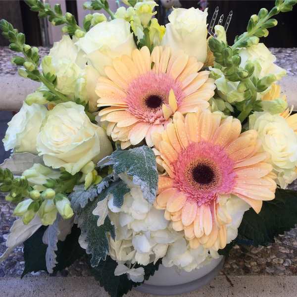 Bouquet of peach gerbera daisies and white roses in a white bowl
