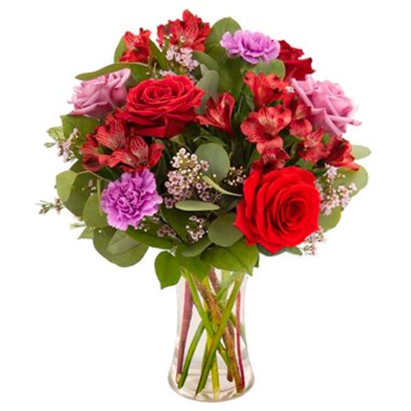 Bouquet of red roses and pink flowers in a clear glass vase