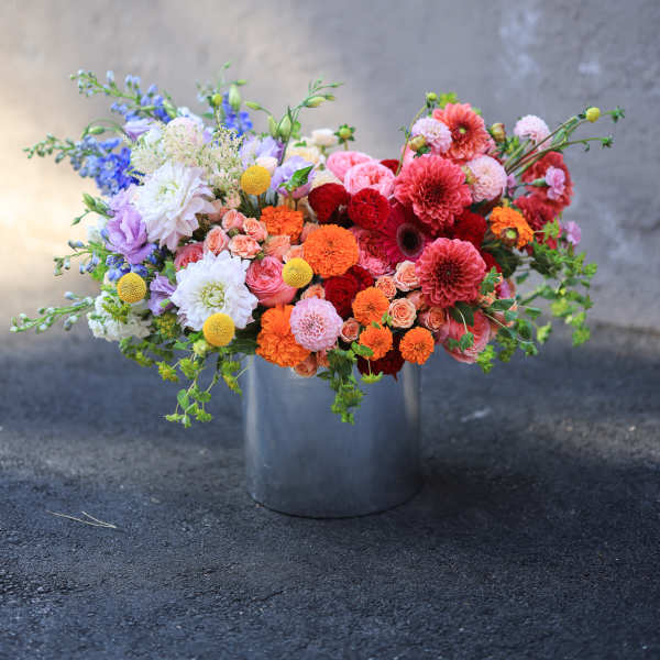 Colorful mixed flower arrangement in a metal bucket