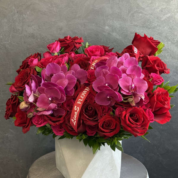 Red roses and pink orchids arranged in a white box