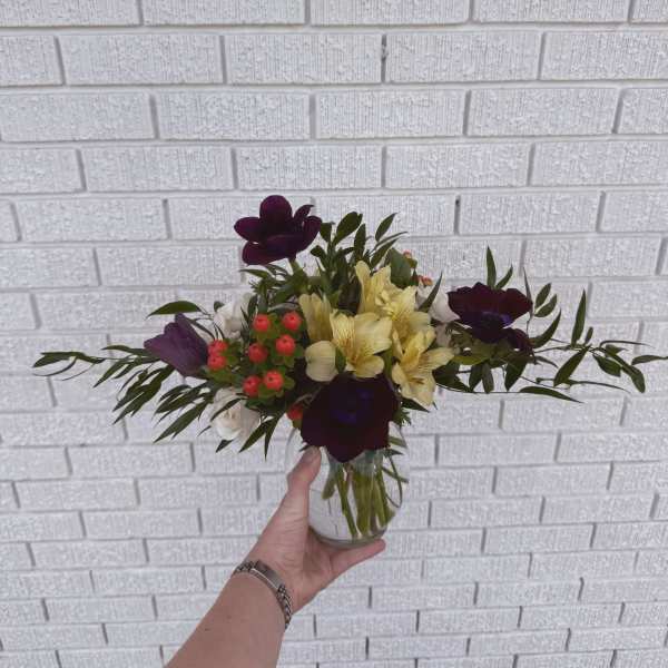 Bouquet of purple and yellow flowers in a clear glass vase
