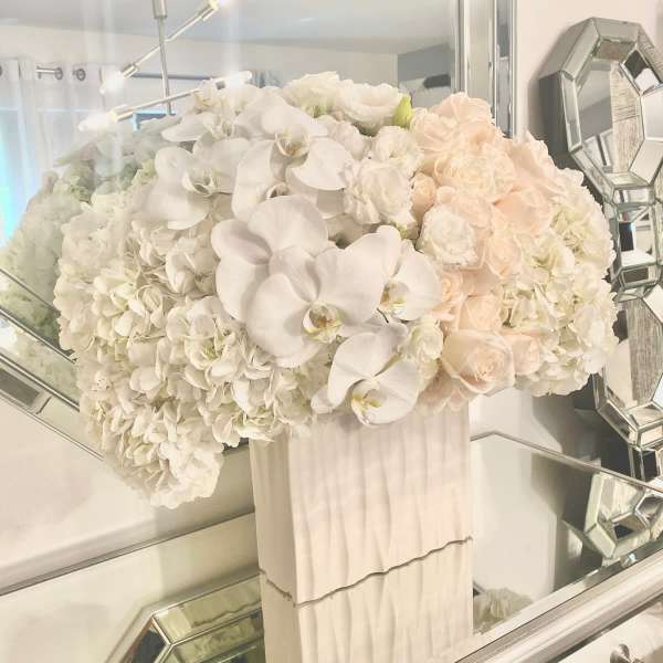 White and blush floral arrangement in a tall white vase