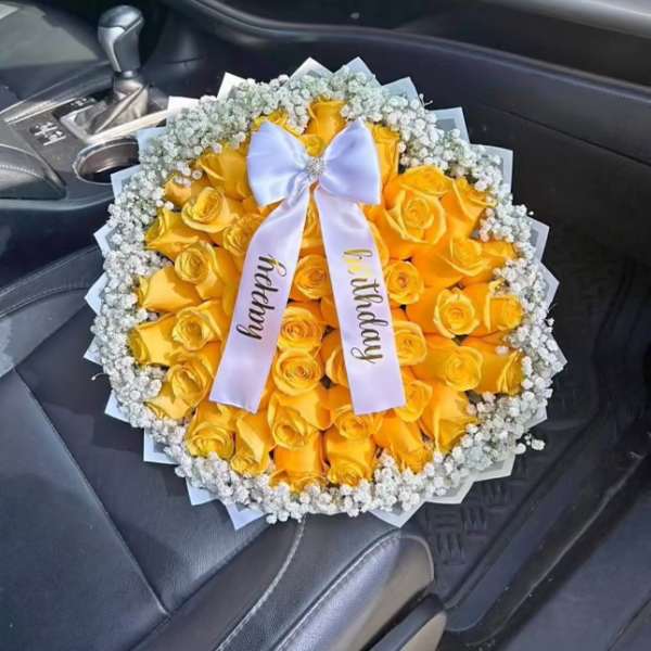 Yellow rose bouquet with a white ribbon in a car seat