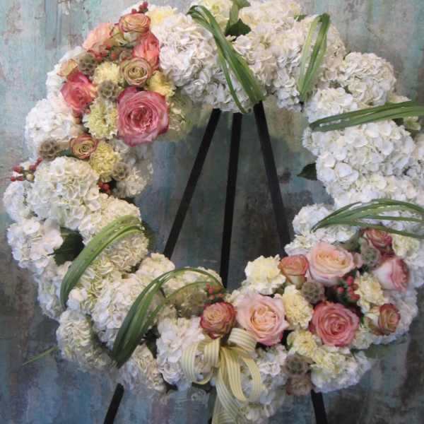 Floral wreath of white hydrangeas and pink roses on a black stand