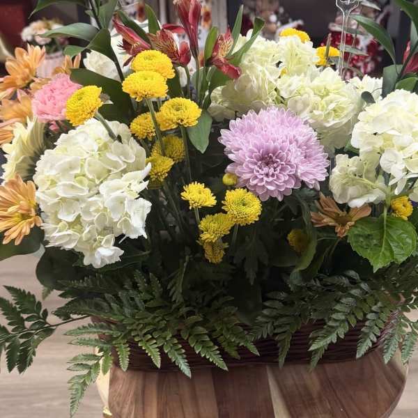 Mixed flower arrangement with white hydrangeas, yellow mums, and a lavender chrysanthemum