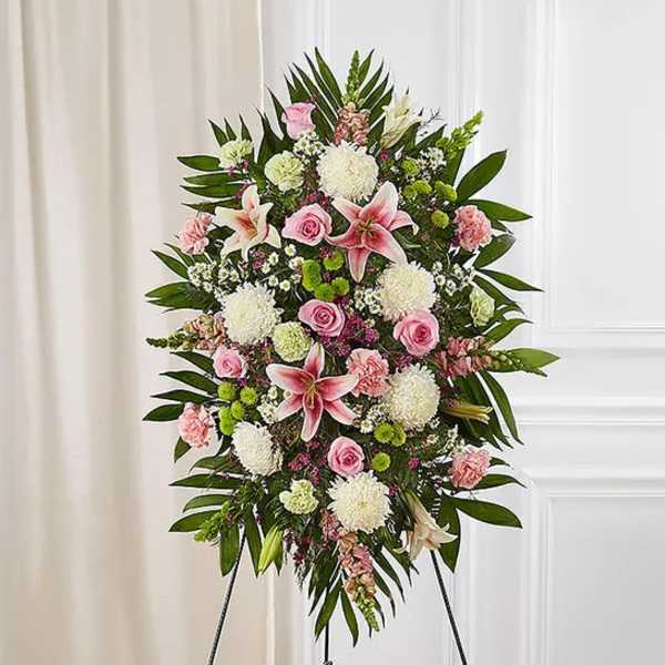 Standing floral spray with pink lilies, roses, and white mums on an easel