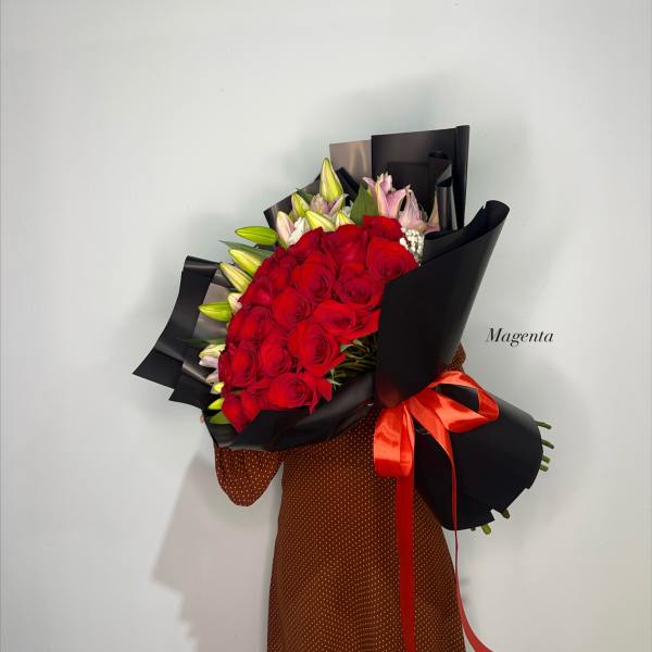 Bouquet of red roses and pink lilies wrapped in black paper