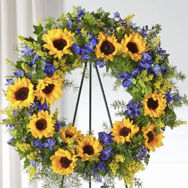 Sunflower wreath with blue and yellow flowers on a stand