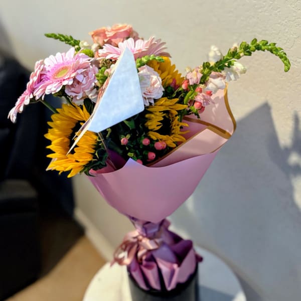 Pink and yellow mixed bouquet wrapped in pastel paper