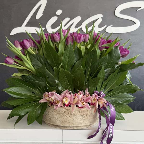 Pink tulips and orchids arranged in a low beige container