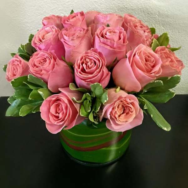 Pink roses arranged in a green round vase