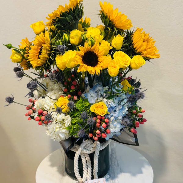 Yellow sunflowers and roses in a black vase with a rope tie