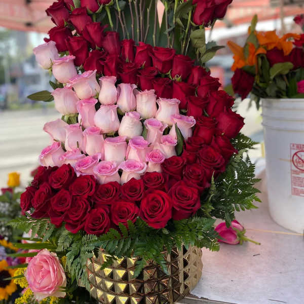 Tiered arrangement of red and pink roses in a gold vase