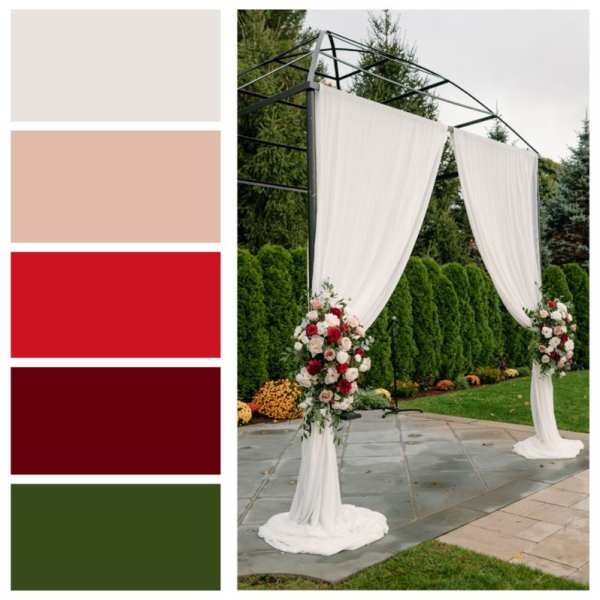 Wedding arch draped in white fabric with red and white floral arrangements