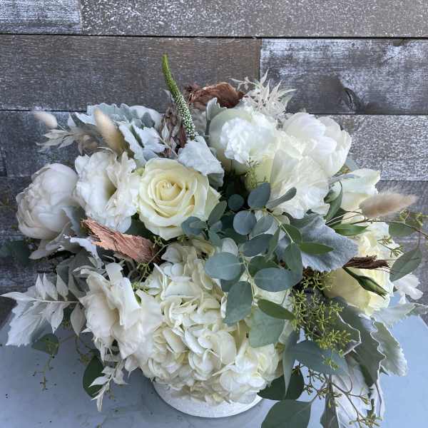 White floral bouquet in a low white container with eucalyptus