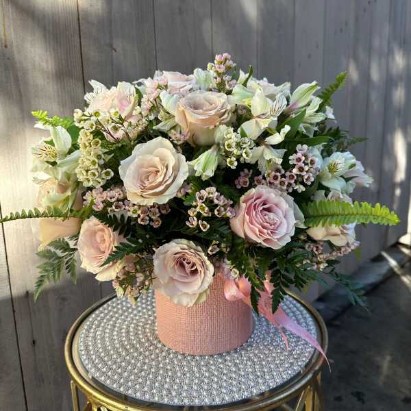 Bouquet of pale pink roses and white flowers in a pink textured box