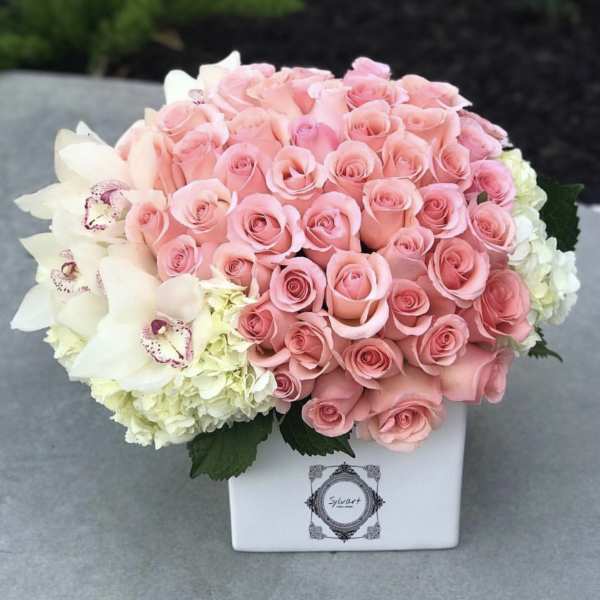 Pink roses and white orchids in a white square vase