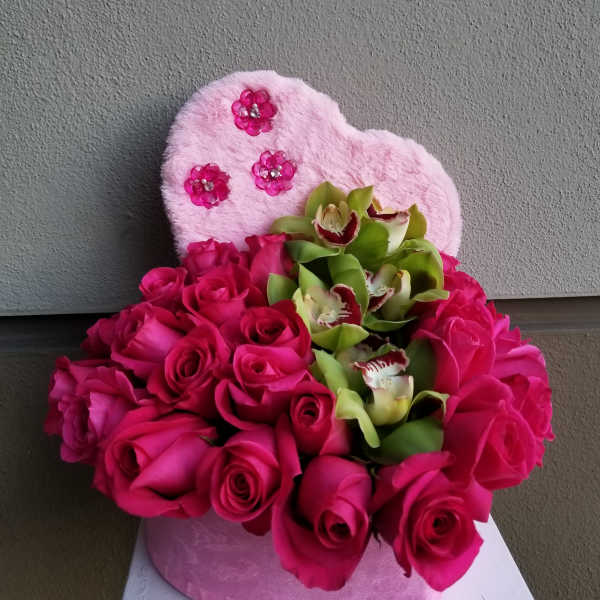 Pink roses and green orchids arranged in a heart-shaped plush box