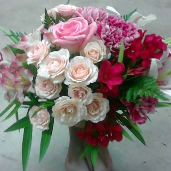 Pink and white rose bouquet in a vase with red accent flowers
