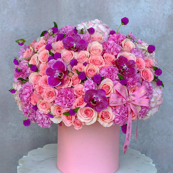Pink rose and orchid arrangement in a round pink box